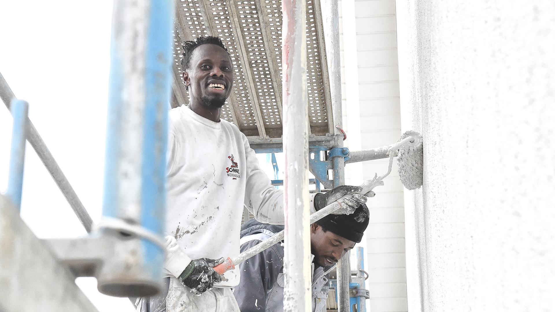 Saikou Bojang, un pittore della ditta di pittura Schwarz a Rheinstetten, è in piedi sull'impalcatura con un collega, intenta a dipingere una casa.