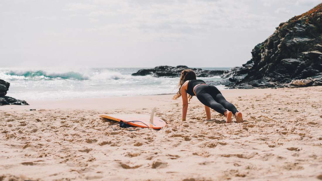 Donna che pratica il surf sulla spiaggia.